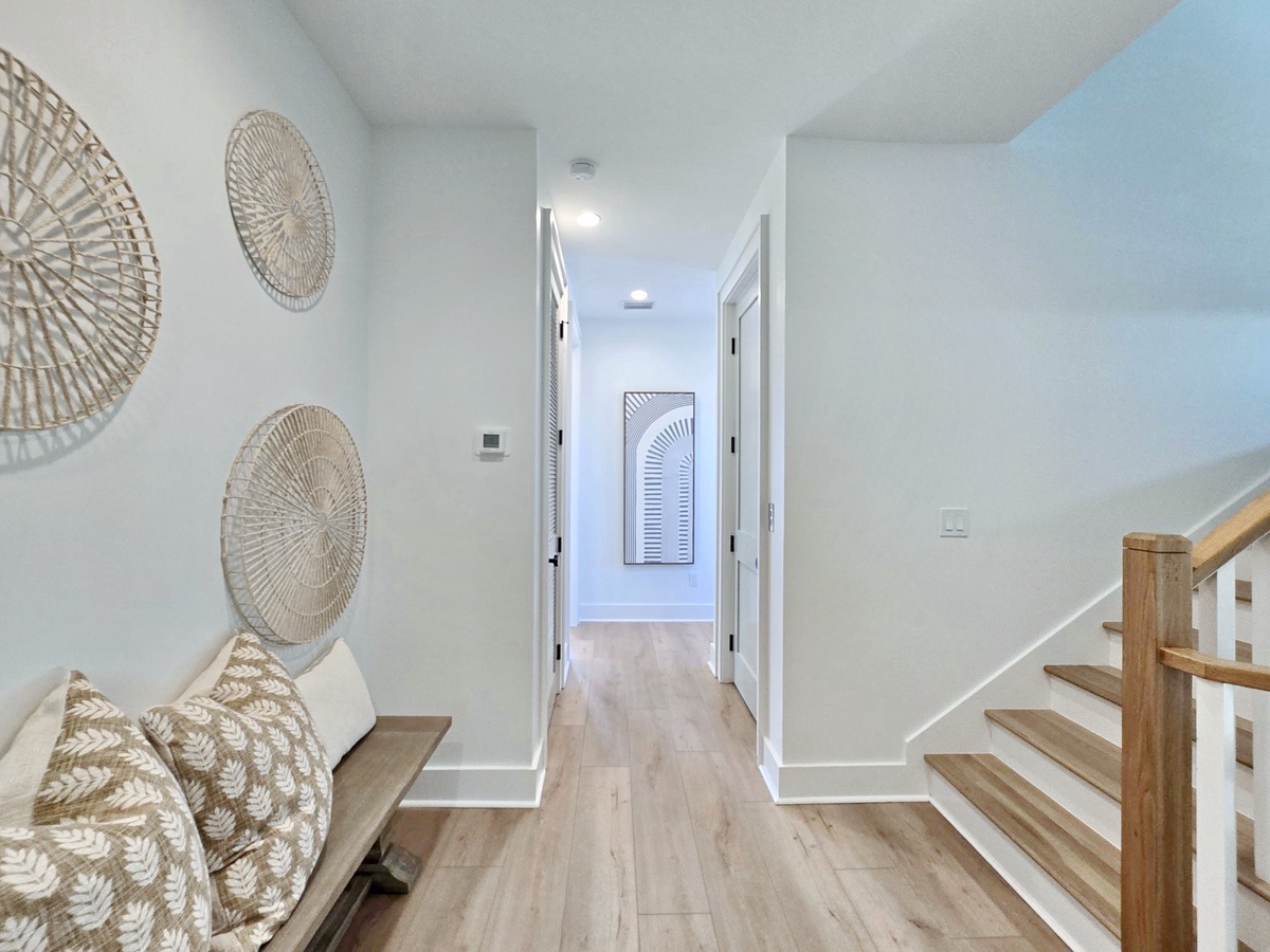 Settle into your private hallway where coastal wicker art and warm wood floors create a peaceful retreat from your adventures.