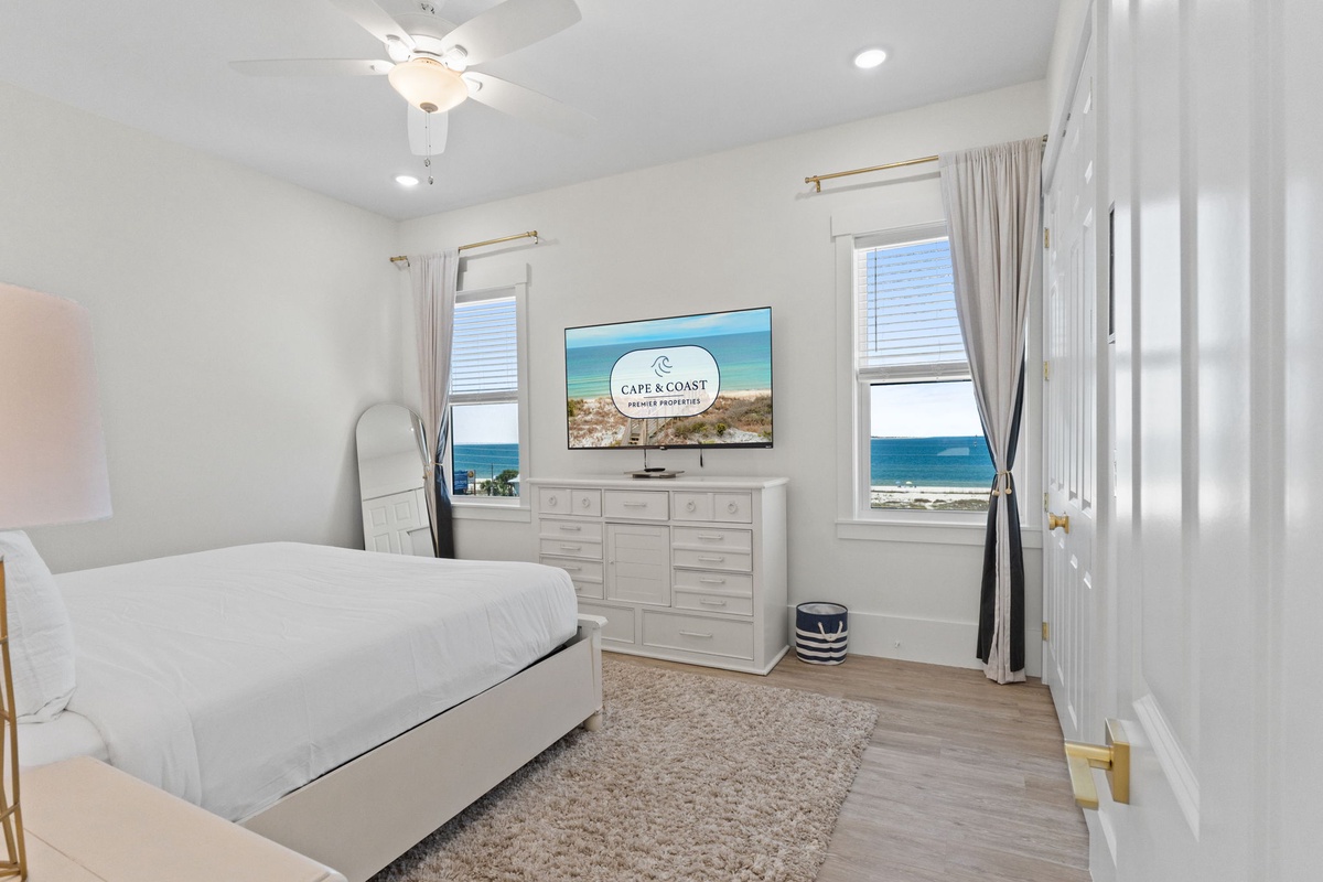 Wake up to stunning ocean views right from your bed. This serene bedroom features modern coastal decor and windows framing the endless blue sea.