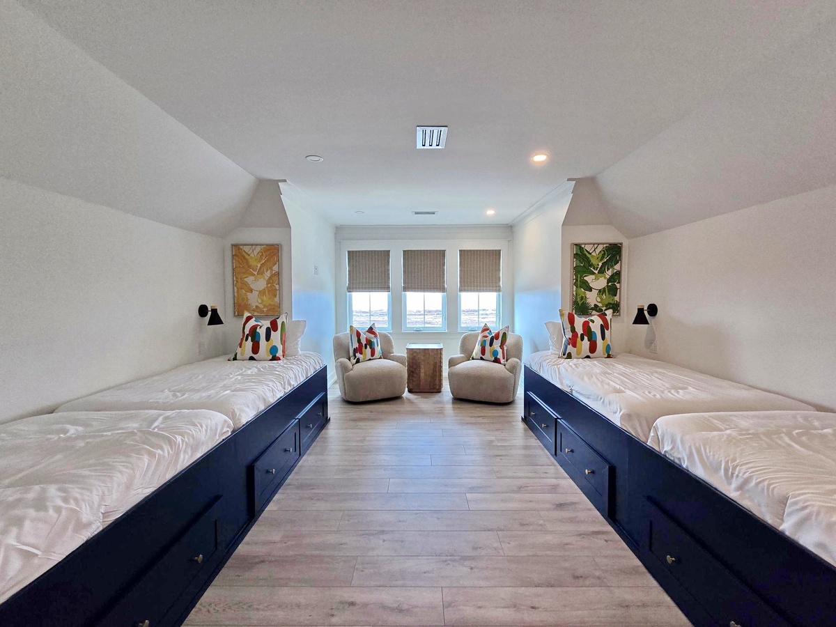 Cozy attic bedroom with twin beds and colorful pillows where you'll wake up to natural light streaming through windows.