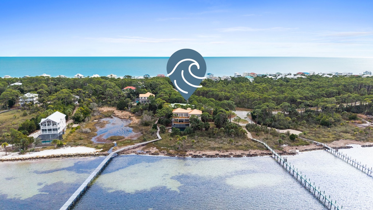 Aerial view of coastal property with private dock access and beachfront location surrounded by natural landscape.