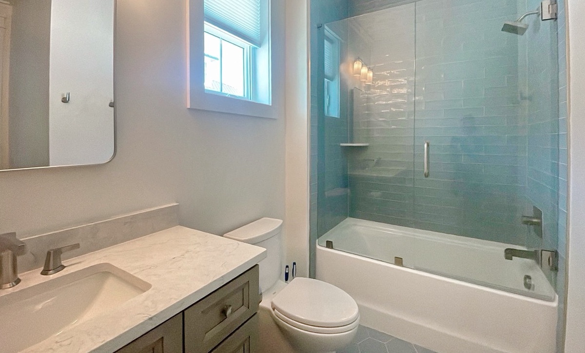 Refresh in your sleek, spa-inspired bathroom with bright tilework, a pristine tub-shower combo, and natural light to start your day feeling renewed.