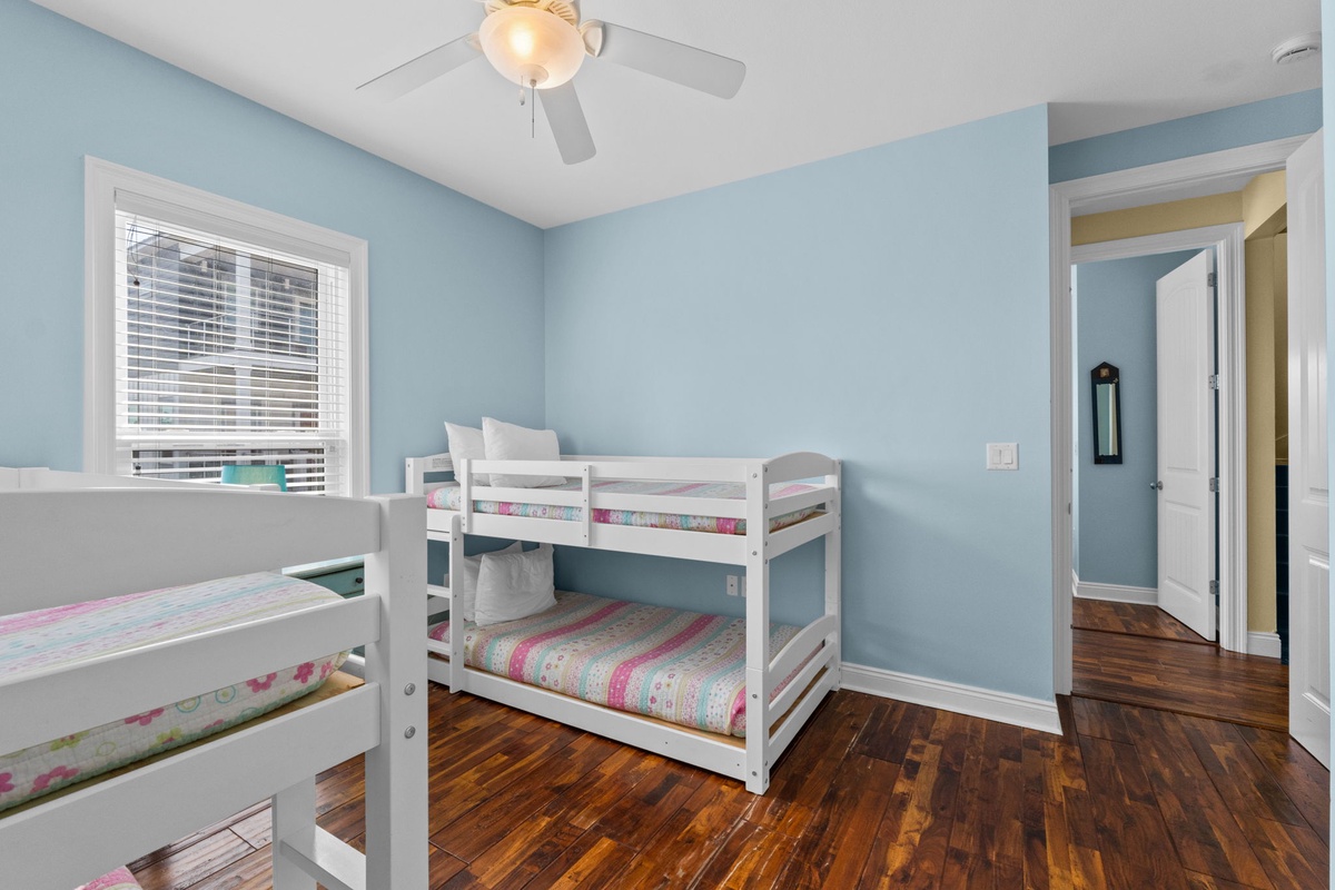 Bright bunk room with serene blue walls and warm hardwood floors, perfect for kids to share and create lasting memories together.