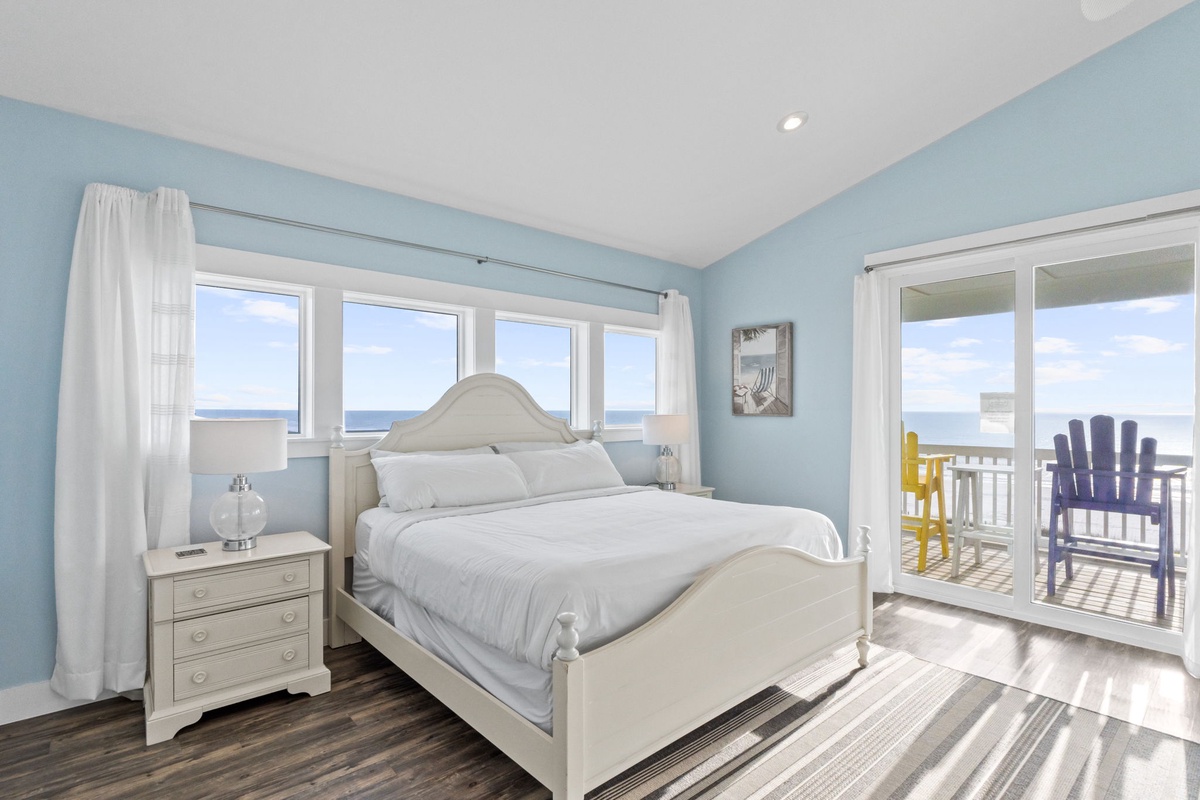 Wake up to endless ocean views in your serene coastal bedroom with direct balcony access and soothing blue décor.