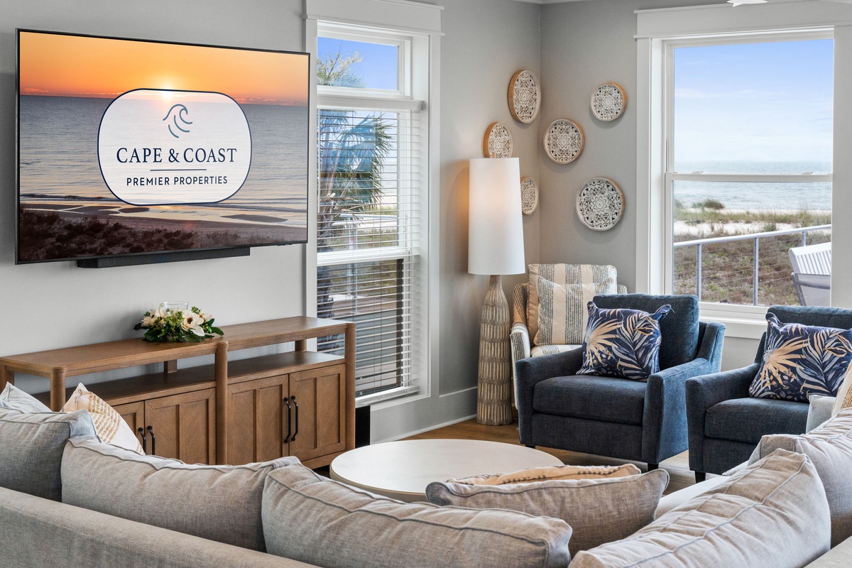 A tasteful coastal living room awaits, featuring plush seating and coastal decor, while windows frame sweeping sea views. The space blends comfort and elegance, perfect for unwinding after beach days.