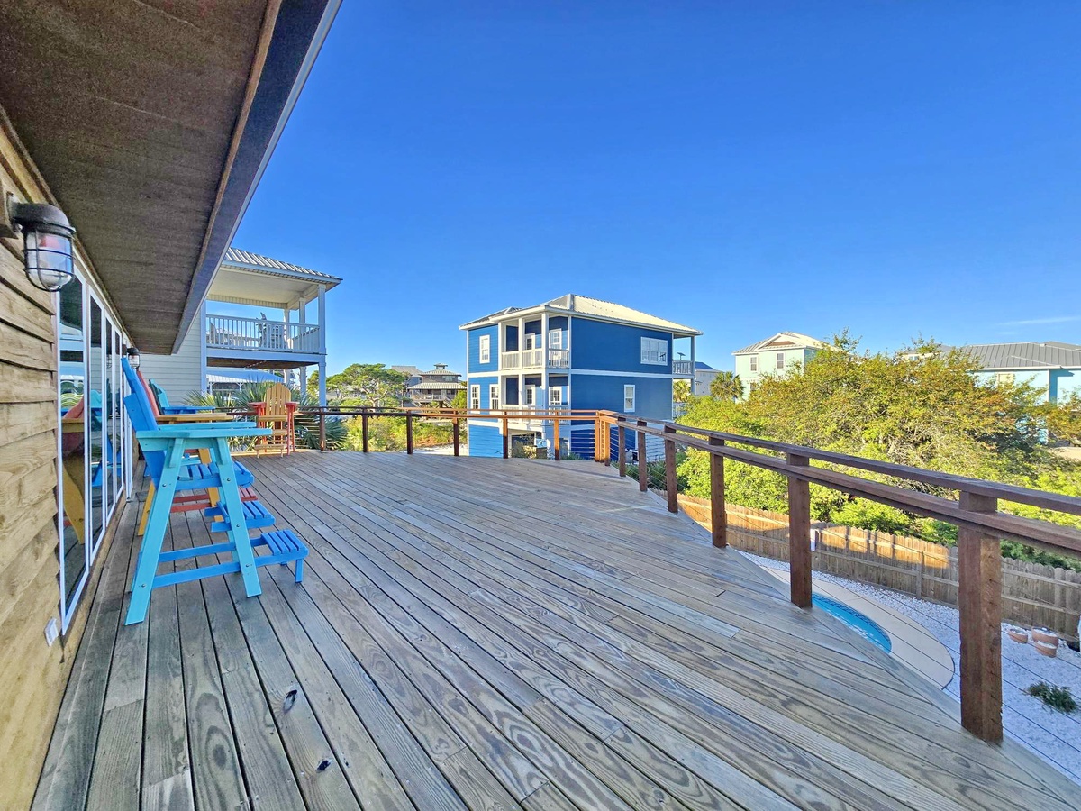 Spacious deck with colorful chairs overlooking neighborhood views under brilliant blue skies.