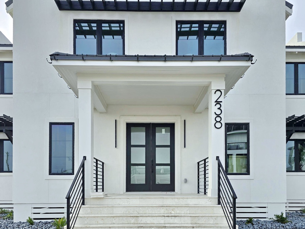 A modern white property building with sleek black accents and glass doors, featuring the address 2330 at the welcoming entrance.