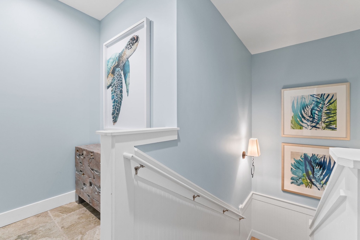 Coastal-inspired artwork and soft blue tones create a calming atmosphere as you move between floors, with tropical and ocean-themed pieces lining your path.