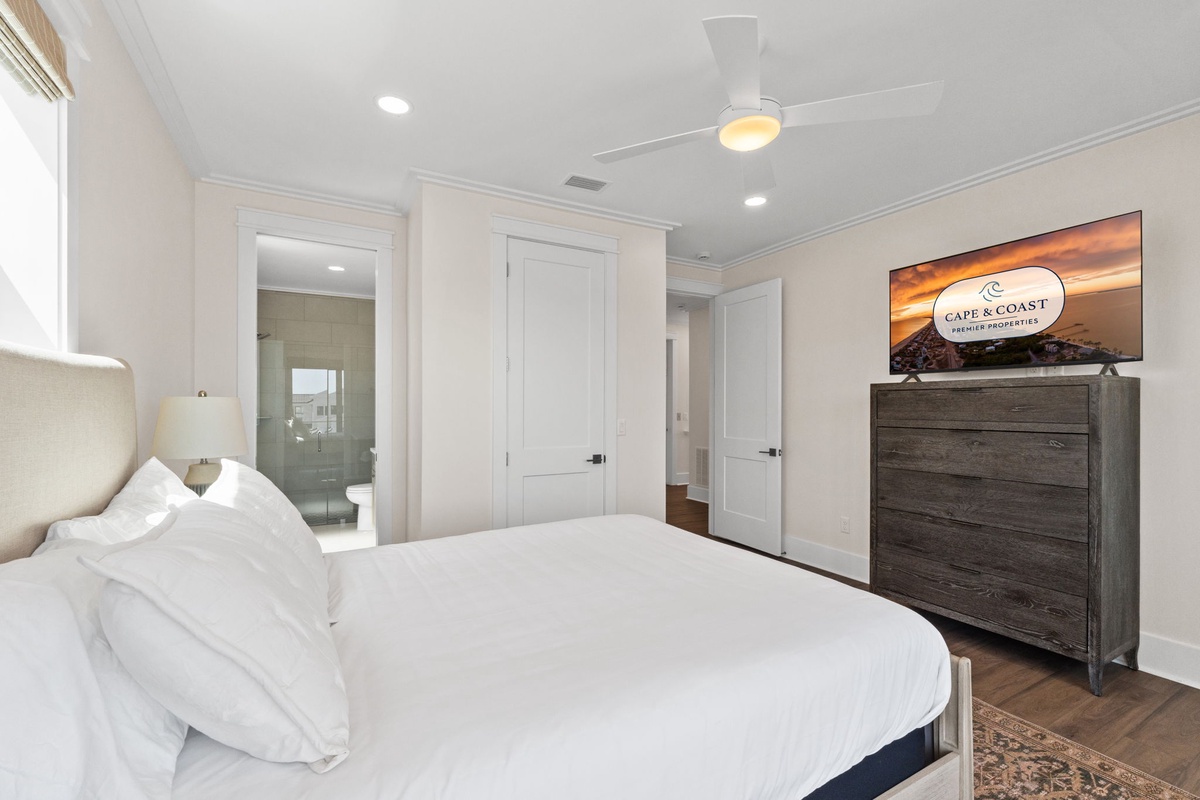 Sink into crisp white linens and wake refreshed in this serene bedroom, complete with an ensuite bath and your own ceiling fan for perfect comfort.