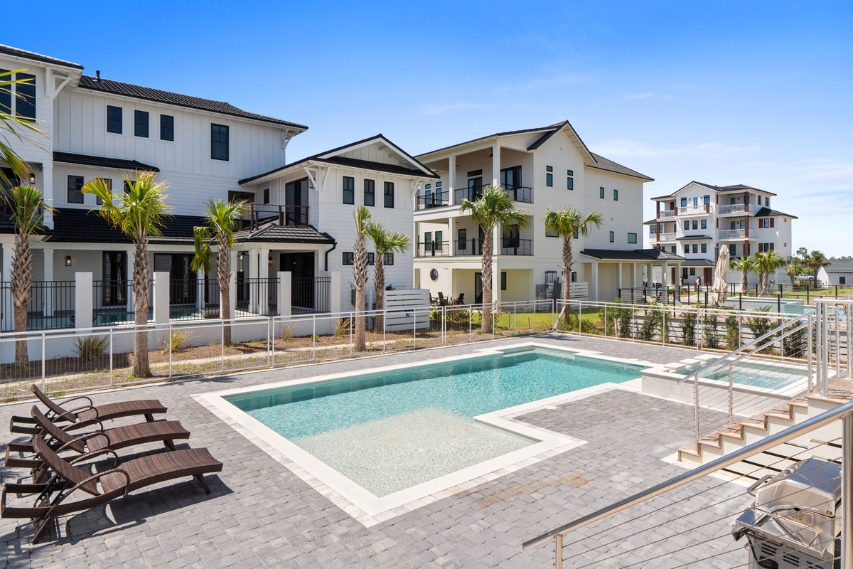 A resort-style community with a refreshing pool deck surrounded by modern townhomes, palm trees, and sunny skies—perfect for your Florida getaway.