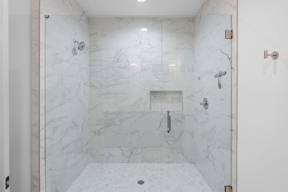 Step into your spa-like shower sanctuary with elegant marble walls and rainfall showerhead for ultimate relaxation.