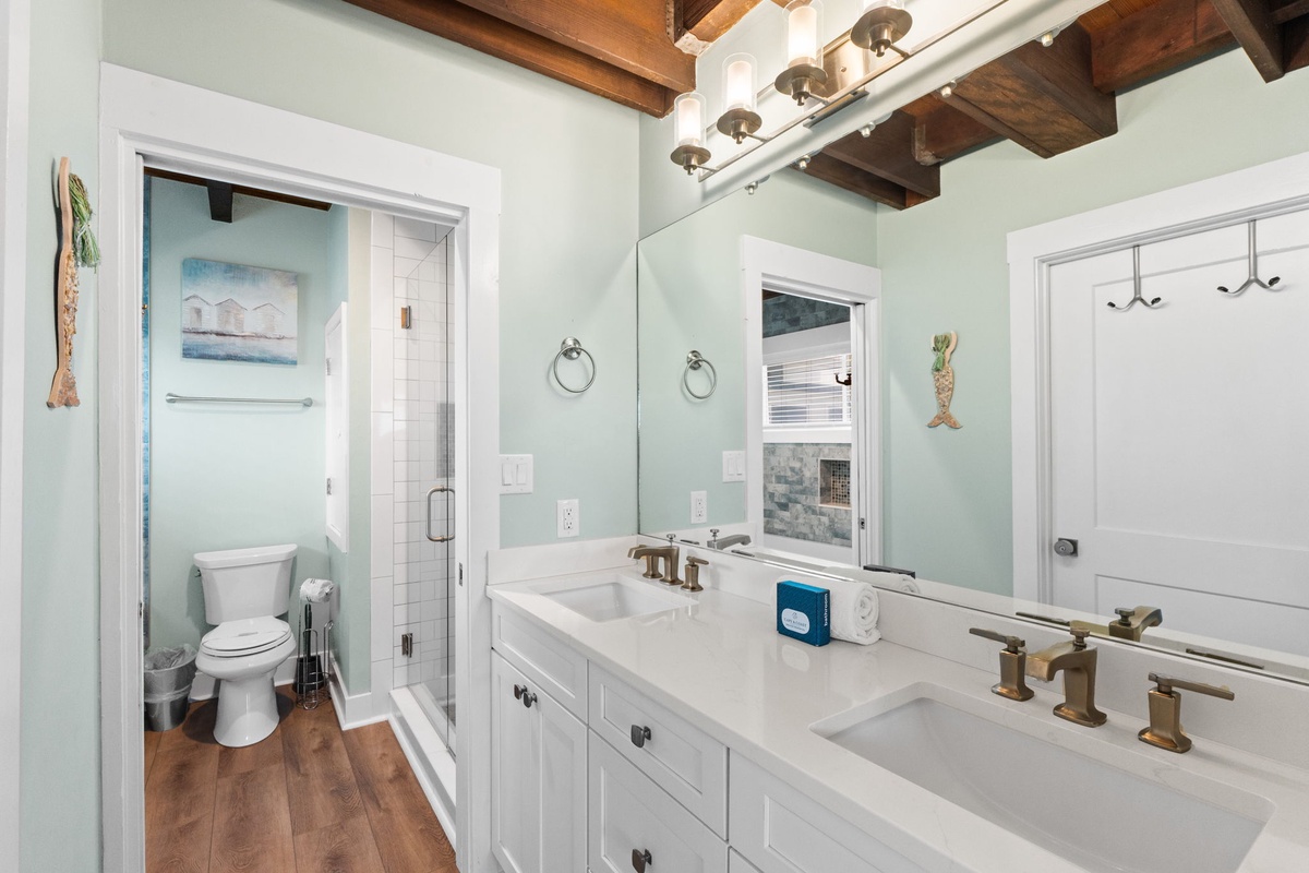 Step into this bright, coastal-inspired bathroom where rustic wood beams meet modern elegance. The dual vanity offers plenty of space to refresh, while the separate water closet and walk-in shower provide comfort and privacy during your stay.