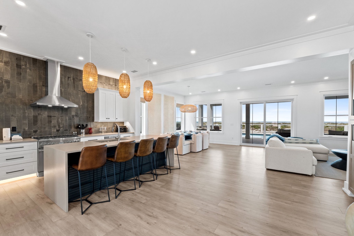 Gather around the spacious kitchen island for morning coffee or evening cocktails, surrounded by warm pendant lighting and panoramic views that fill the open living space with natural light.