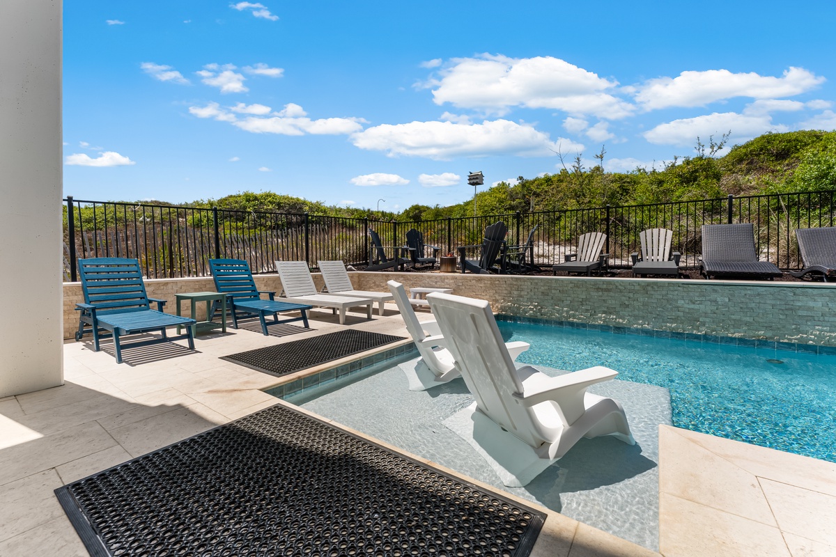 Dive into your private pool oasis with built-in loungers and spacious deck seating, surrounded by peaceful natural landscapes.