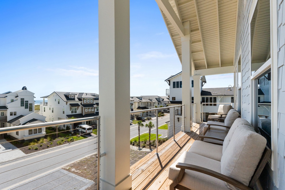 Step onto your covered balcony where coastal breezes meet modern comfort. Settle into plush seating and let the neighborhood views complete your peaceful escape.