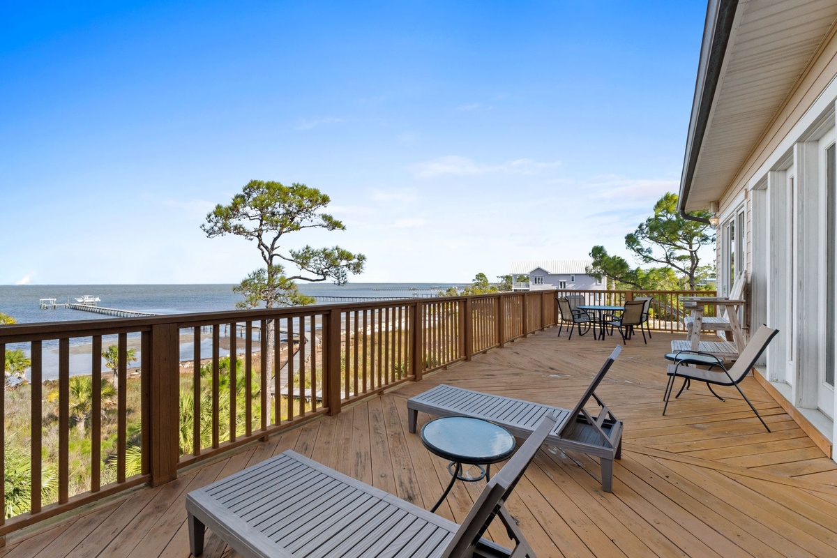 Expansive waterfront deck with comfortable seating overlooking serene bay waters and coastal landscape.