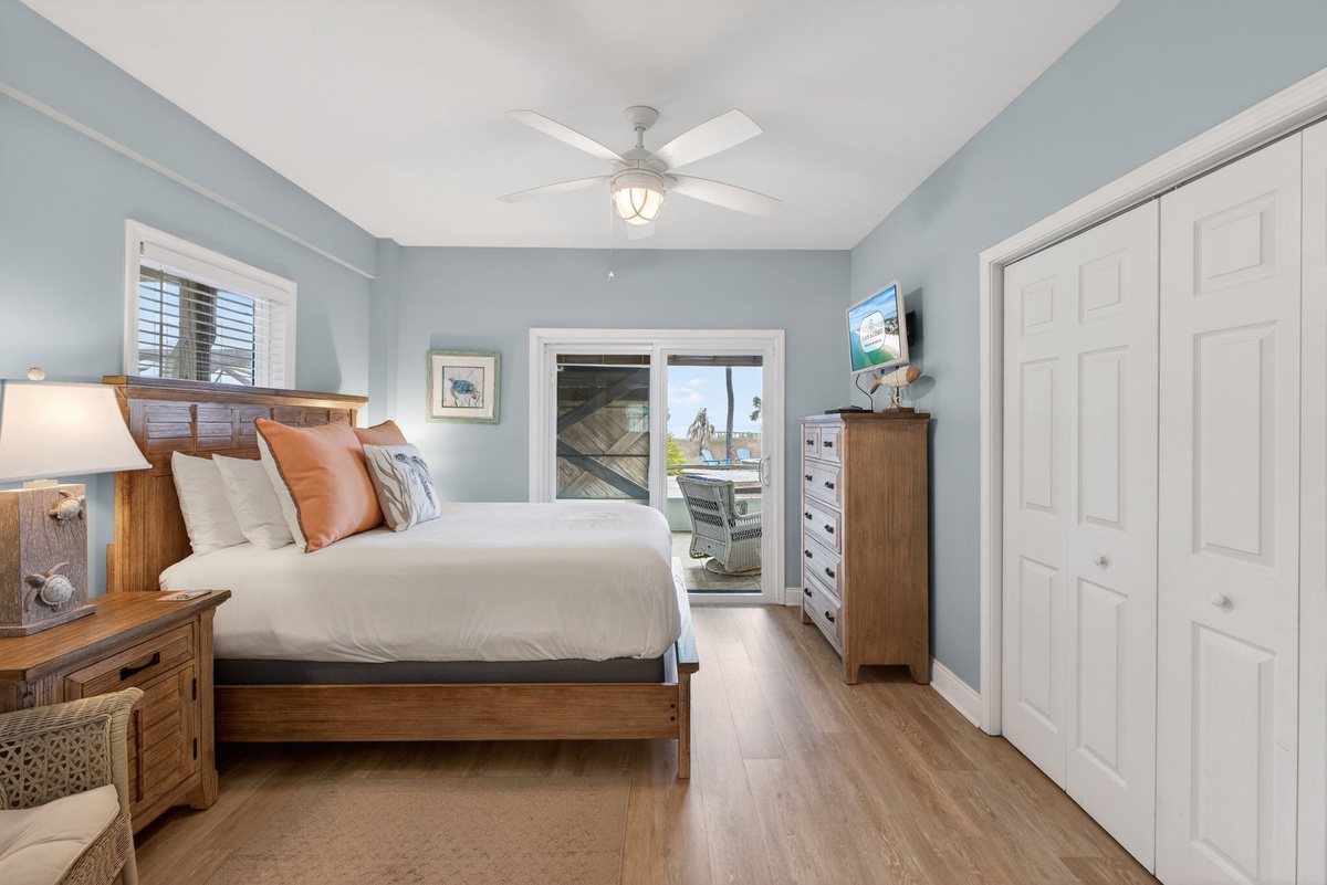 Relax in your peaceful bedroom with soothing blue walls, warm wood furnishings, and a ceiling fan keeping you comfortable.