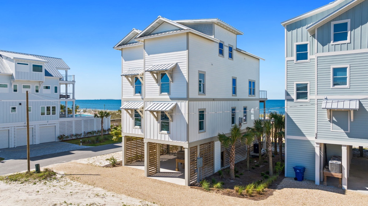 Bright beachside property with modern coastal architecture, palm trees, and direct ocean access in a sunny vacation community.
