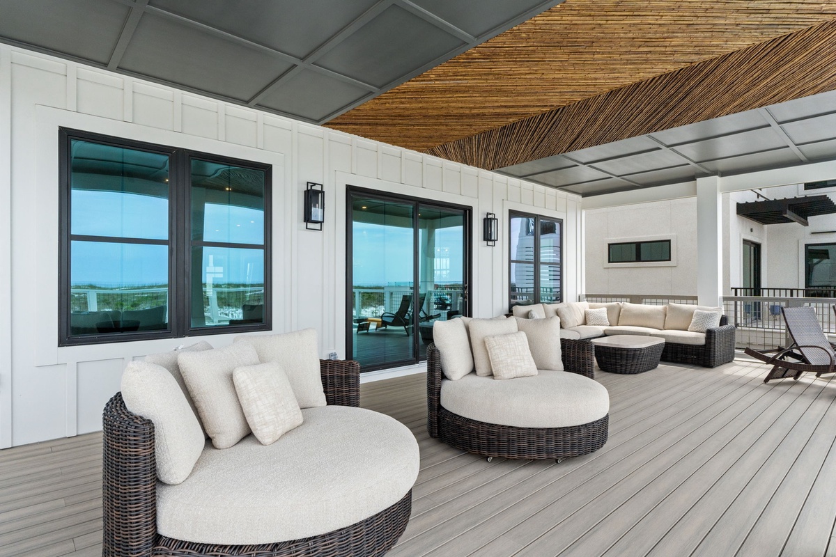 Step onto the expansive rooftop terrace and sink into plush lounge seating, where coastal breezes drift beneath the thatched canopy and sweeping water views frame your peaceful escape.