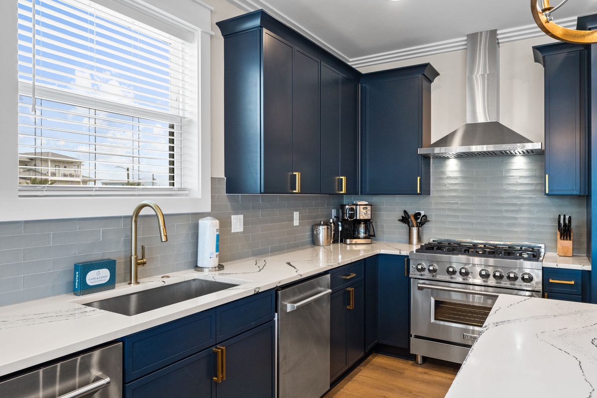 Your fully equipped kitchen features elegant navy cabinetry, premium stainless appliances, and a gleaming gas range—perfect for preparing memorable meals during your stay.