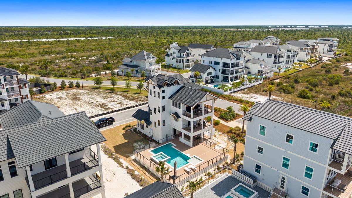 Aerial view of beachside community featuring modern vacation homes with private pools and coastal architecture.