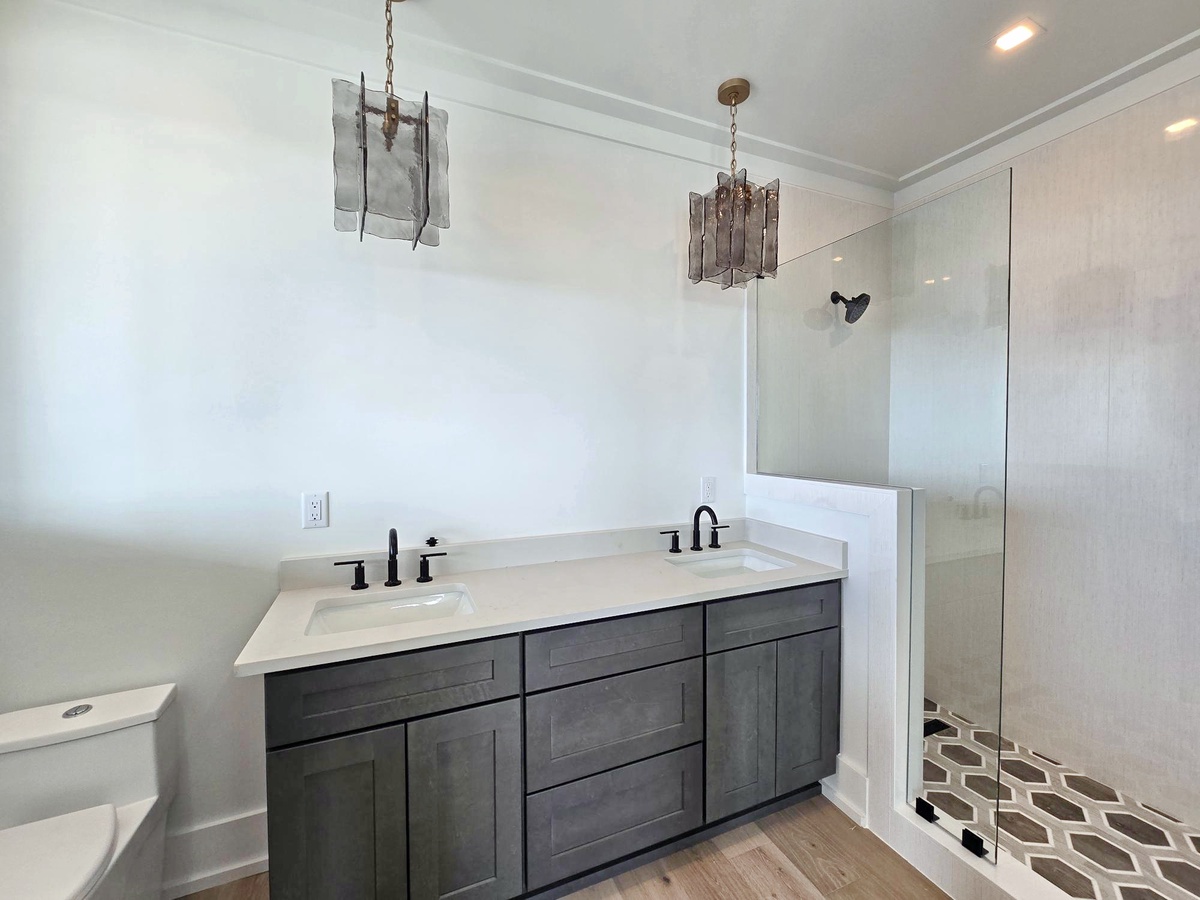 Step into your elegantly appointed bathroom featuring dual vanities and a sleek glass-enclosed shower—perfect for refreshing mornings.