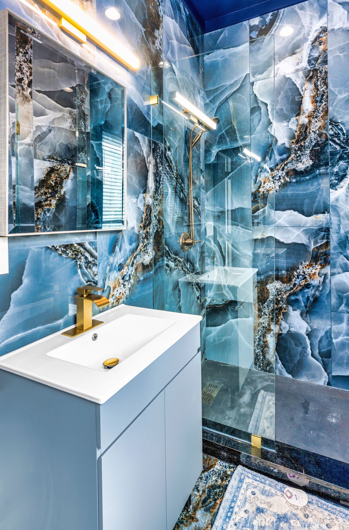 Step into your stunning bathroom featuring dramatic blue marble walls and luxurious gold fixtures that create a spa-like sanctuary for your stay.