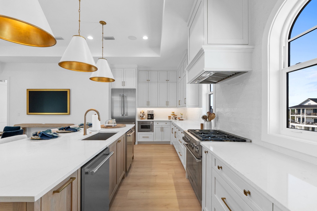 Your culinary haven awaits with gleaming white marble countertops, professional-grade gas range, and warm golden pendant lighting creating the perfect space for memorable meals.