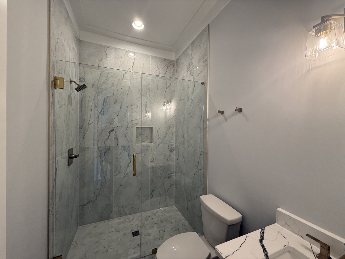Step into your luxurious marble-clad bathroom featuring an elegant glass-enclosed shower and modern fixtures for your ultimate comfort.