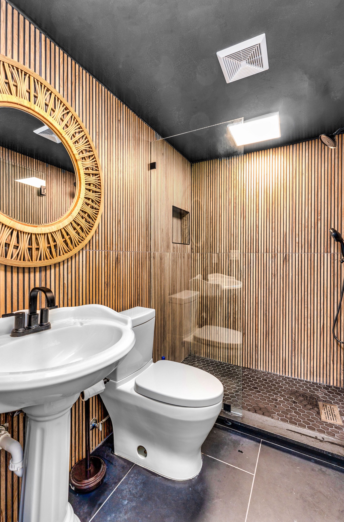 Unwind in your stunning spa-like bathroom featuring warm bamboo walls, rainfall shower, and elegant pedestal sink for ultimate relaxation.