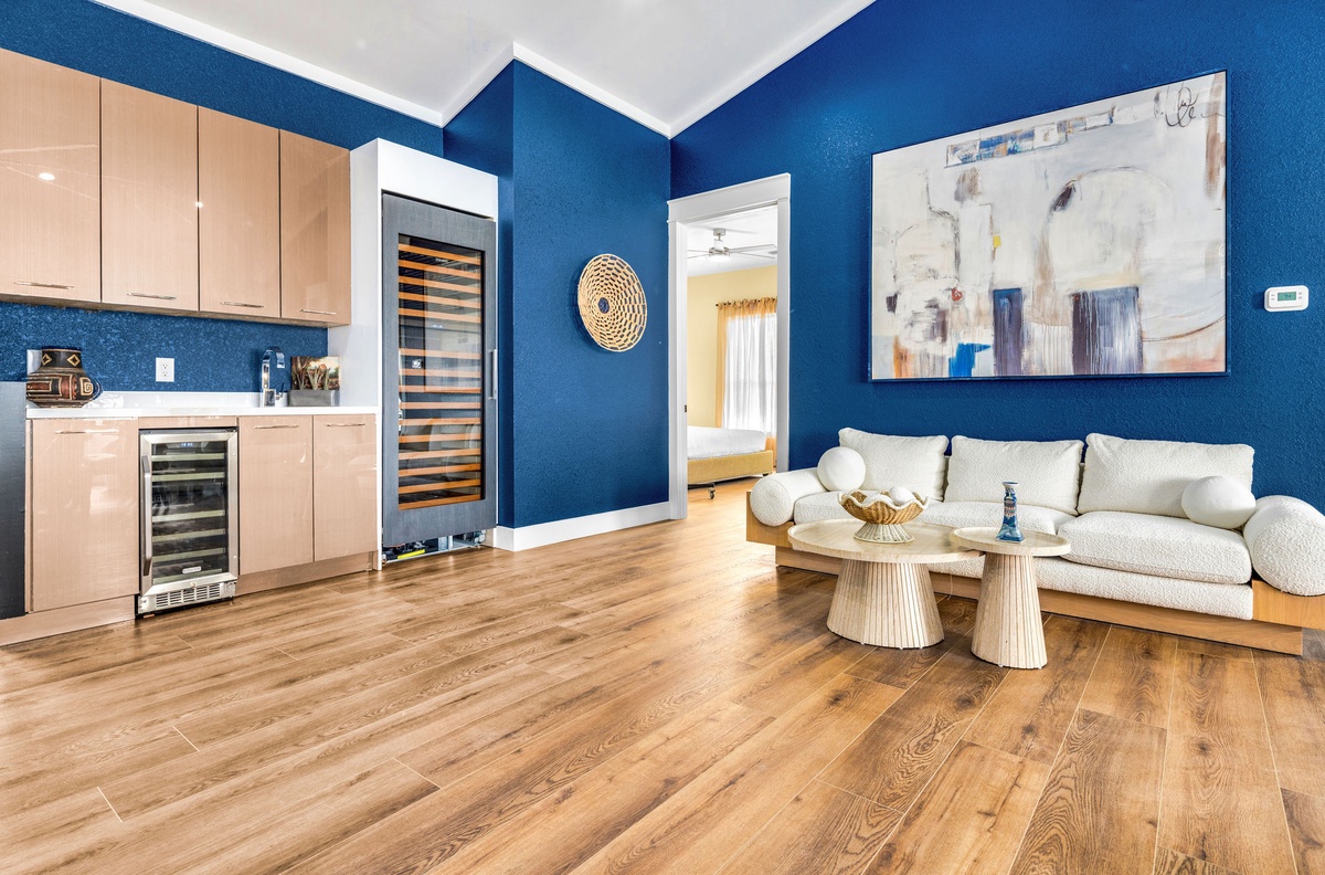Unwind in this stylish open-plan living space where vibrant blue walls meet warm wood floors, creating your perfect home away from home.
