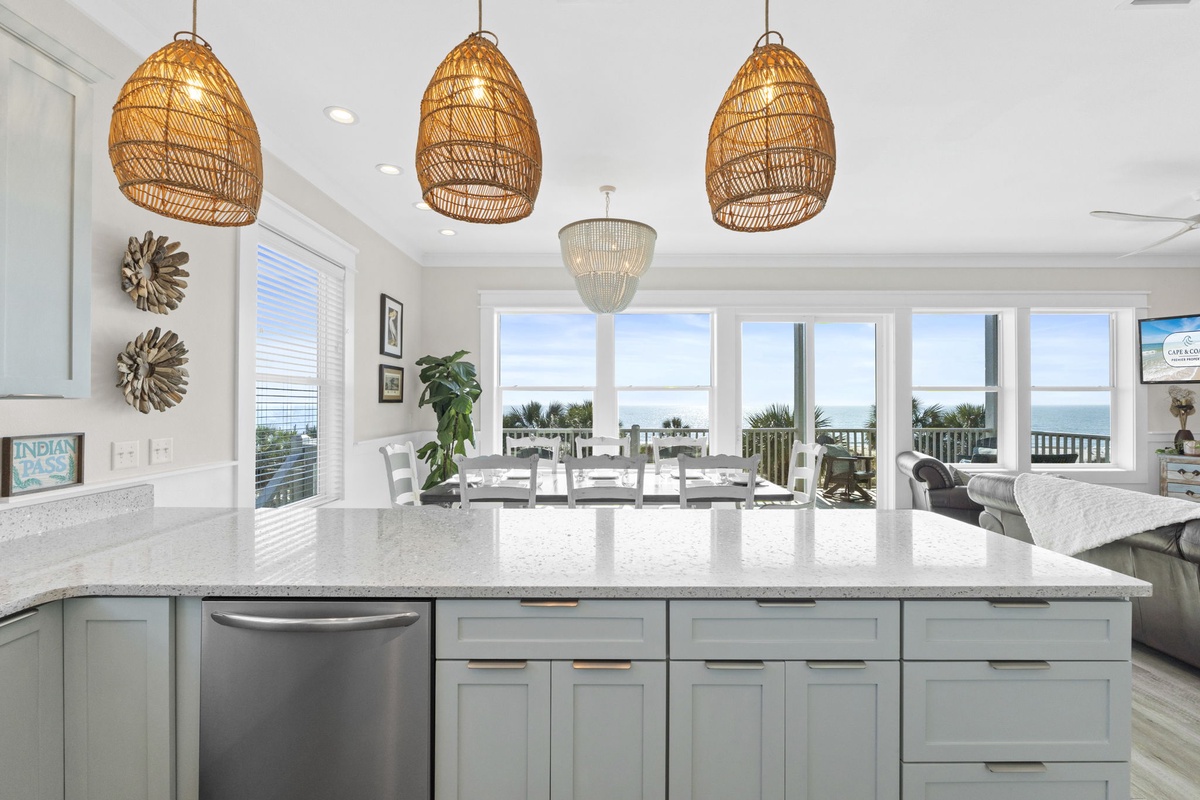 Your dream kitchen awaits with stunning ocean views, elegant wicker pendant lights, and spacious granite counters perfect for morning coffee.