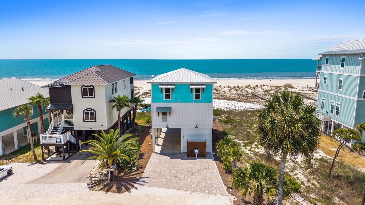 Beachfront property with turquoise waters and white sand just steps from the door, nestled among coastal palms.