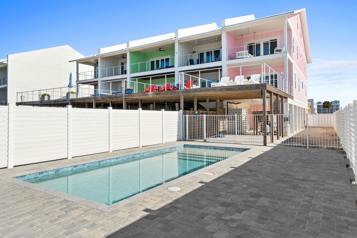 Modern beachside property featuring colorful apartments with balconies and a shared swimming pool area.