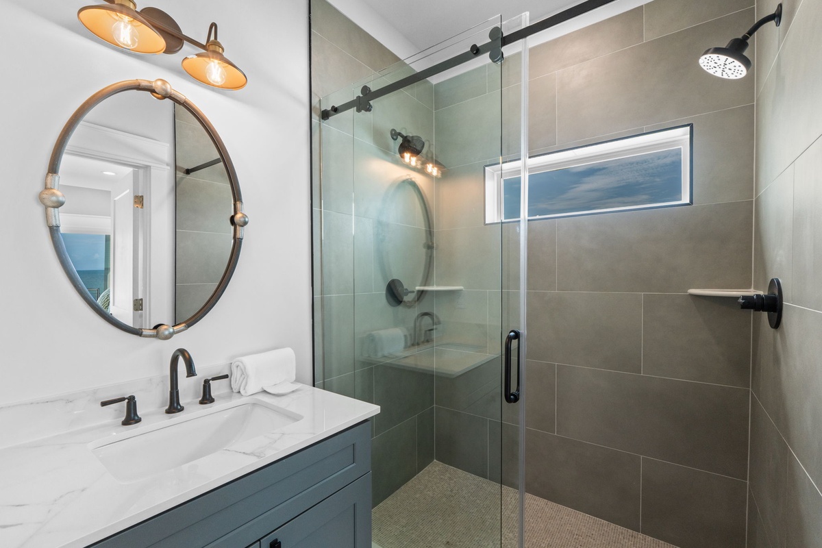 Step into your private sanctuary with a spacious walk-in shower, elegant fixtures, and marble-topped vanity. Natural light streams through a tranquil window, making every morning feel refreshing.