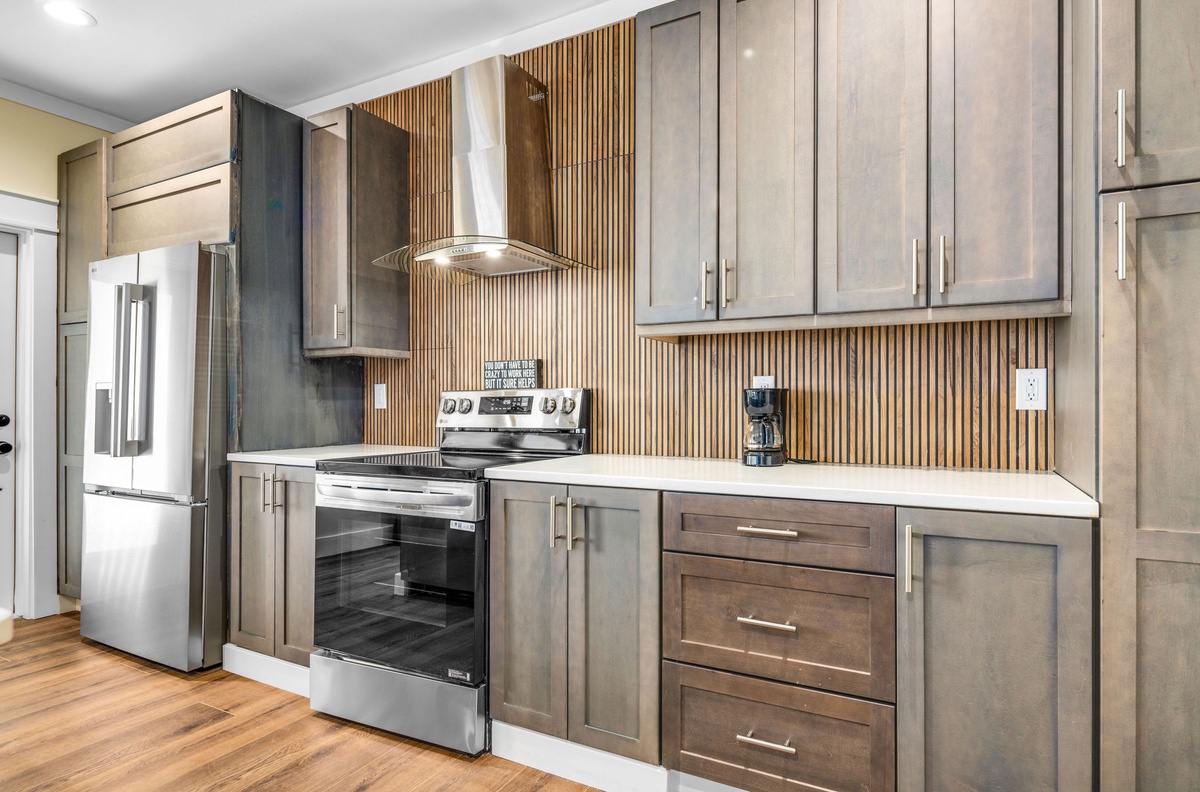 You'll love creating meals in this modern kitchen with sleek gray cabinets, stainless steel appliances, and a striking wood backsplash.