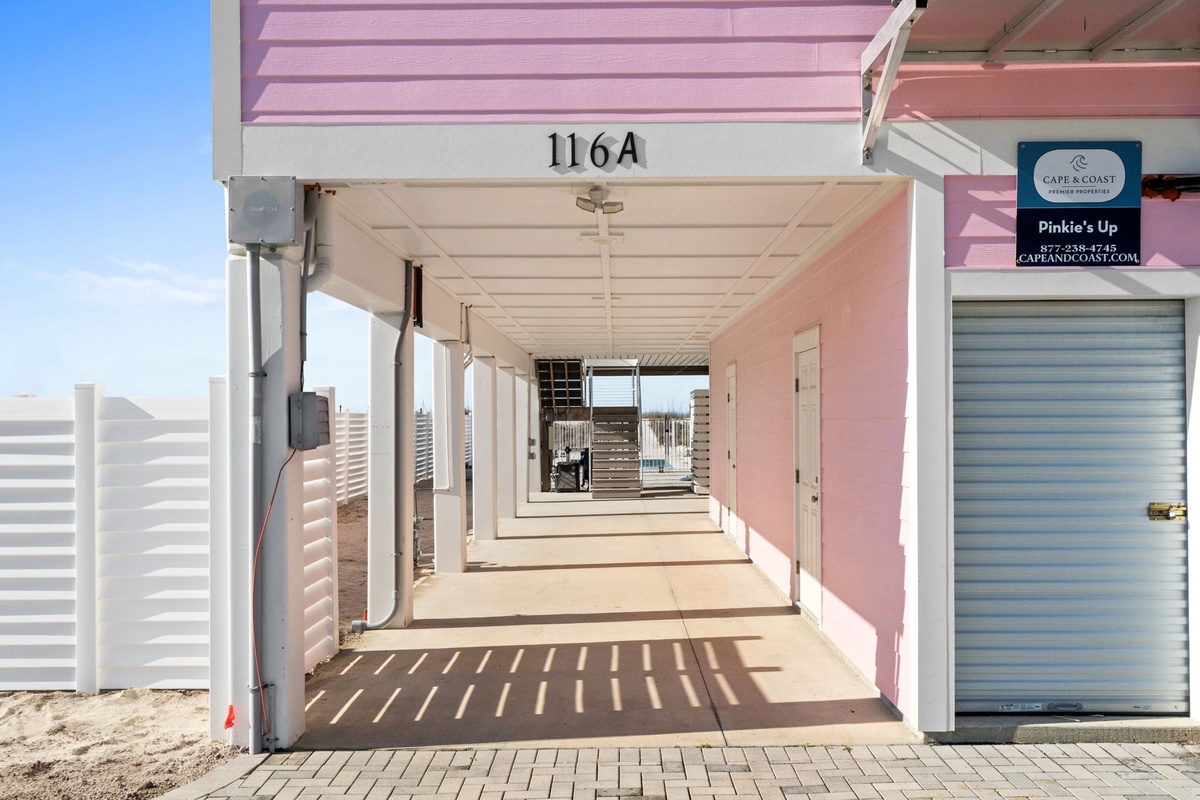 A covered walkway leads to your private beachside retreat, where pink walls and coastal charm create the perfect seaside escape.