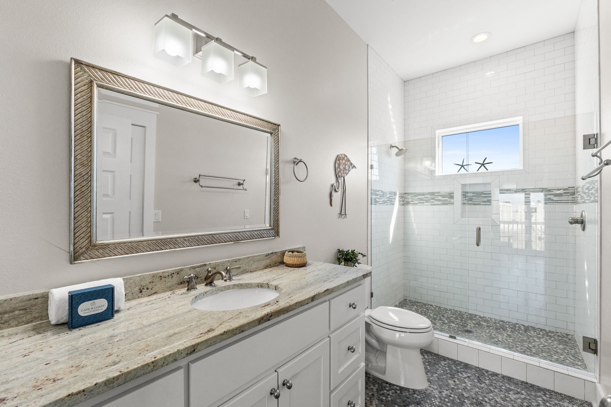 Refresh in your elegant bathroom featuring a luxurious walk-in shower, granite countertops, and coastal-themed touches that perfectly complement your beachside retreat.