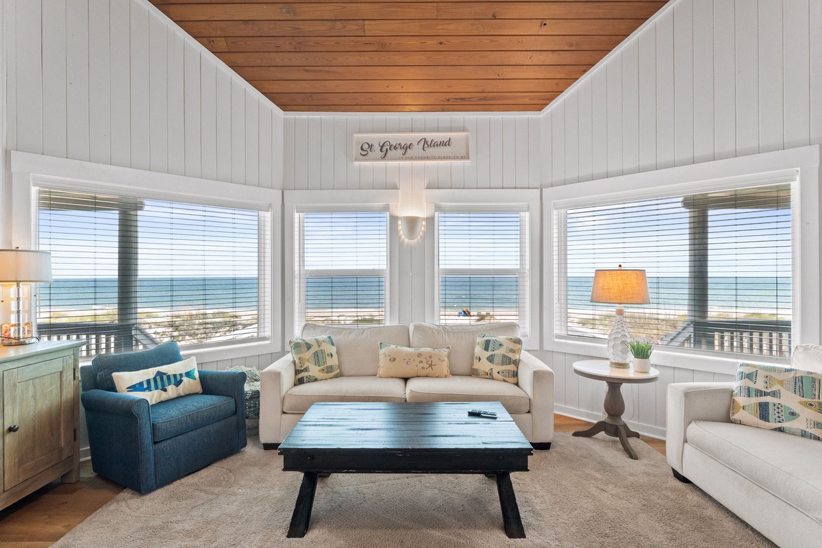 Picture yourself unwinding in this bright, coastal living room with sweeping ocean views through every window—your peaceful retreat where the sea is always within sight.