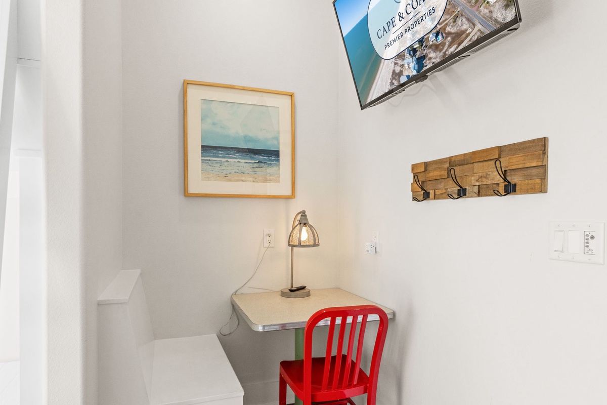Your cozy workspace overlooks coastal charm with beachy artwork and a warm desk lamp for productive mornings or evening planning.