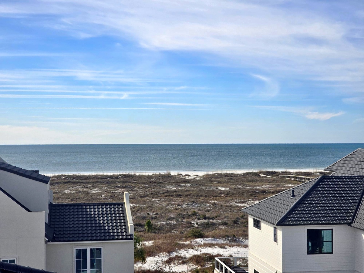 Coastal vacation rental area with direct beach access and ocean views beyond the dunes.