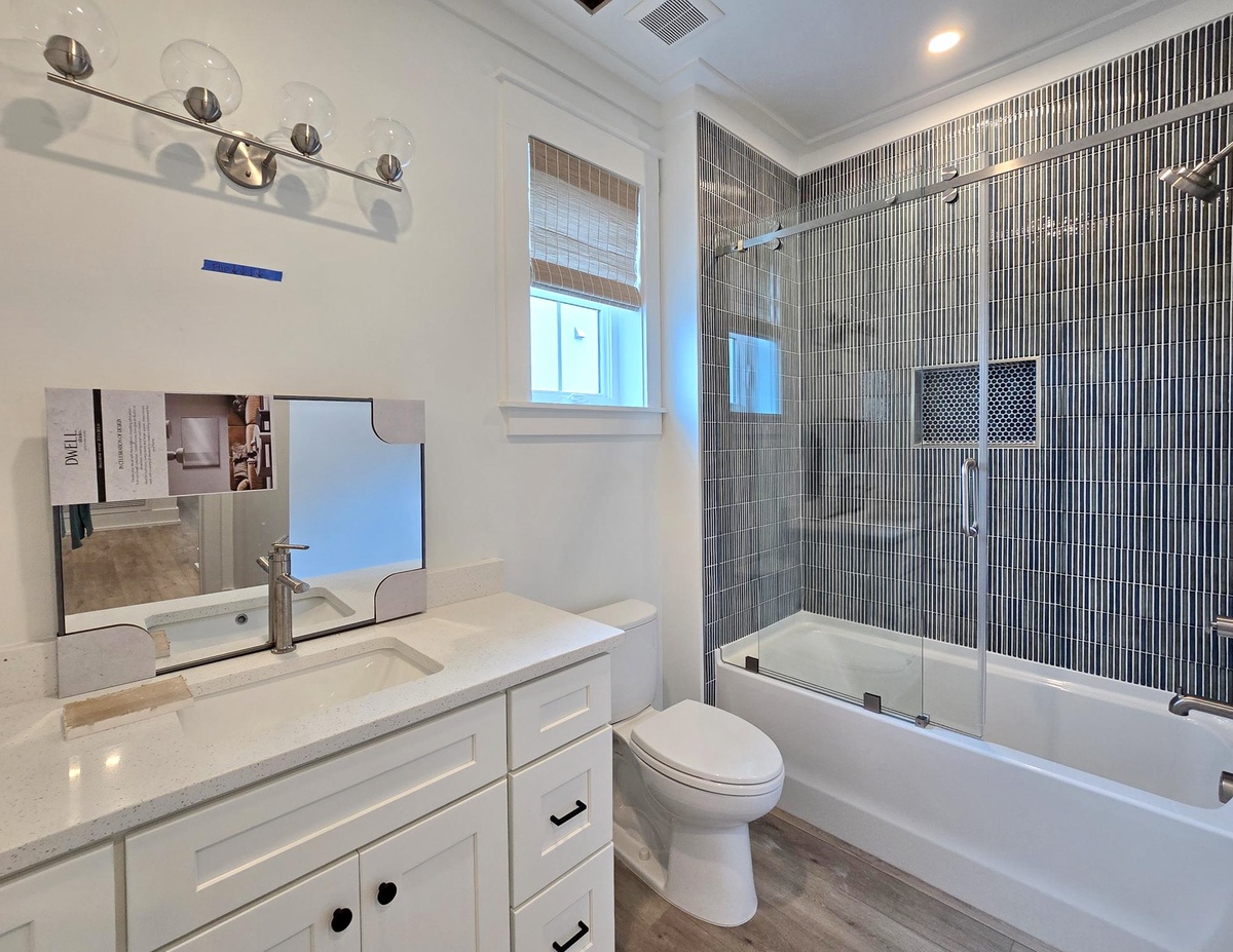 Your luxurious bathroom features elegant tiled walls, sparkling vanity lighting, and a glass-enclosed tub perfect for unwinding after exploring.