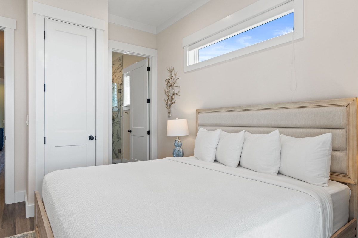 Sink into crisp white linens in this bright, airy bedroom where natural light streams through windows above your comfortable bed.