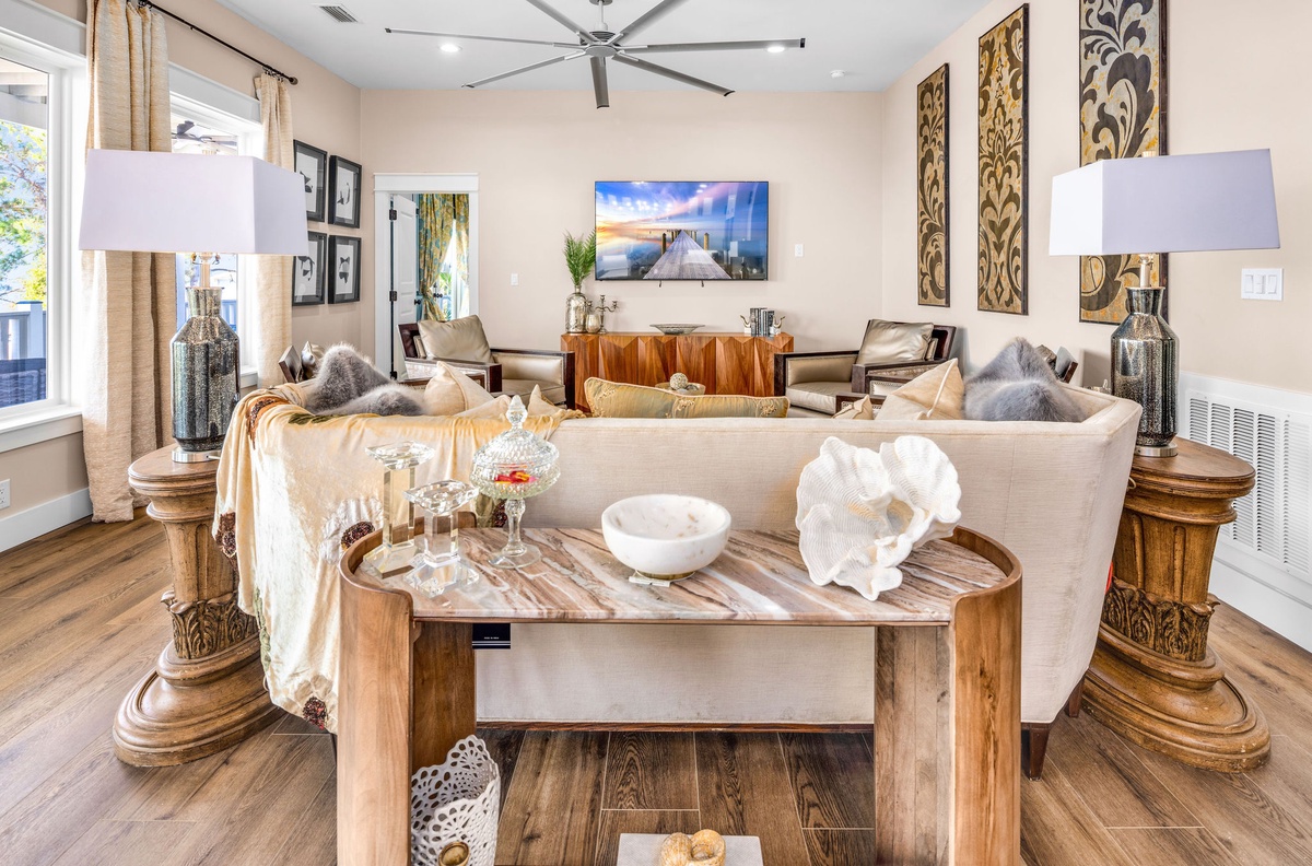 Sink into plush cream sofas surrounded by warm wood tones and coastal artwork. Your elegant living space offers comfort and style.