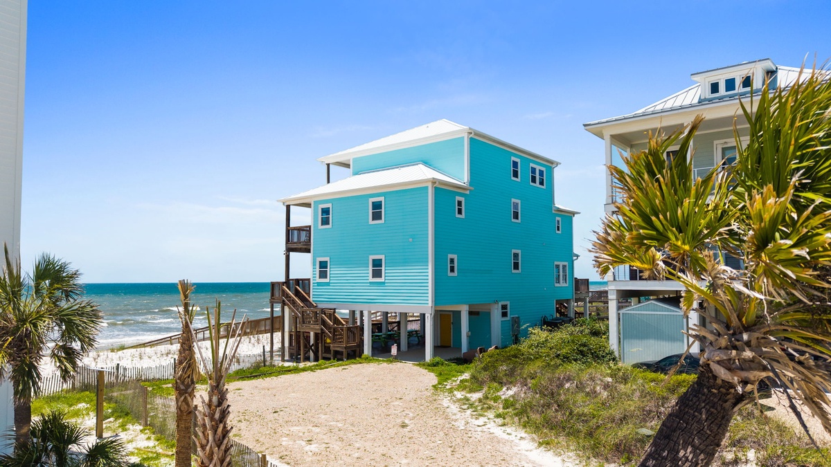 Beachfront vacation homes on stilts with tropical landscaping and direct sandy beach access, offering oceanfront views in a coastal setting.