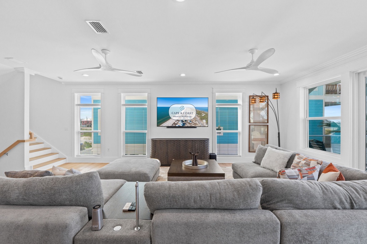 Sink into plush sofas while ocean breezes drift through your sunlit retreat. Floor-to-ceiling windows frame endless sea views, and modern comfort meets coastal tranquility in this elegant living space.