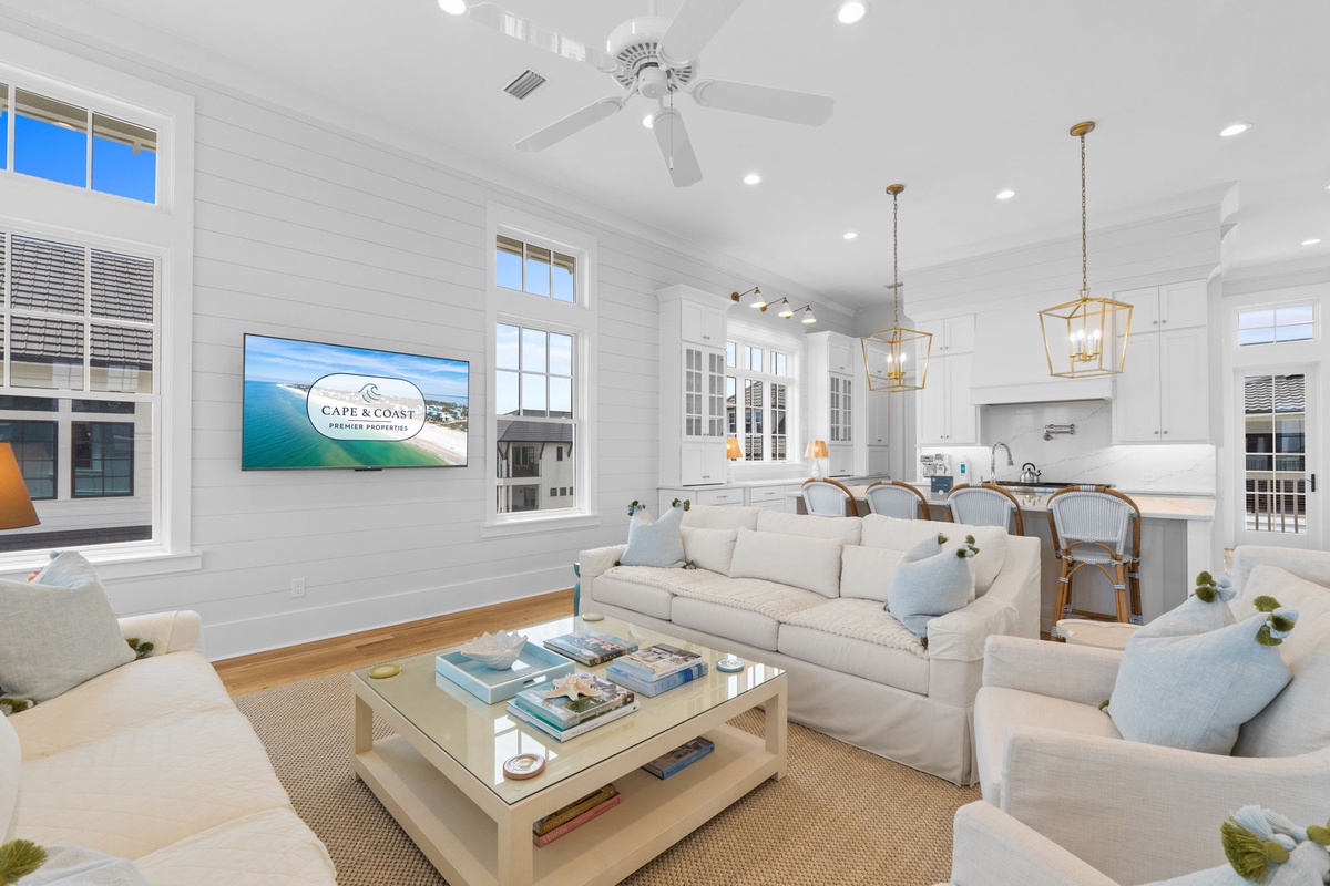 Settle into this airy open-concept living space where coastal elegance meets comfort. Soft white shiplap, plush seating, and warm wood tones invite you to relax after sun-filled beach days.