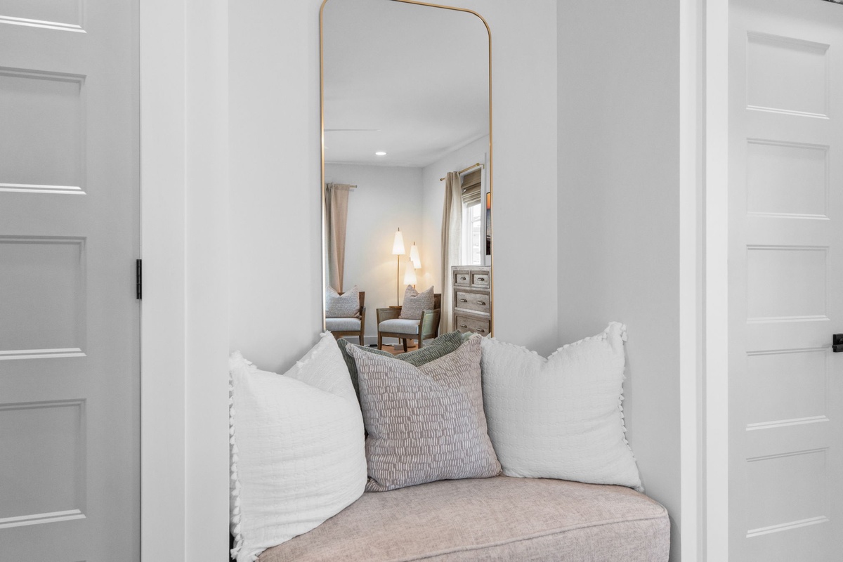 Curl up in your cozy reading nook with soft pillows and elegant mirror, perfectly nestled between rooms for quiet moments.