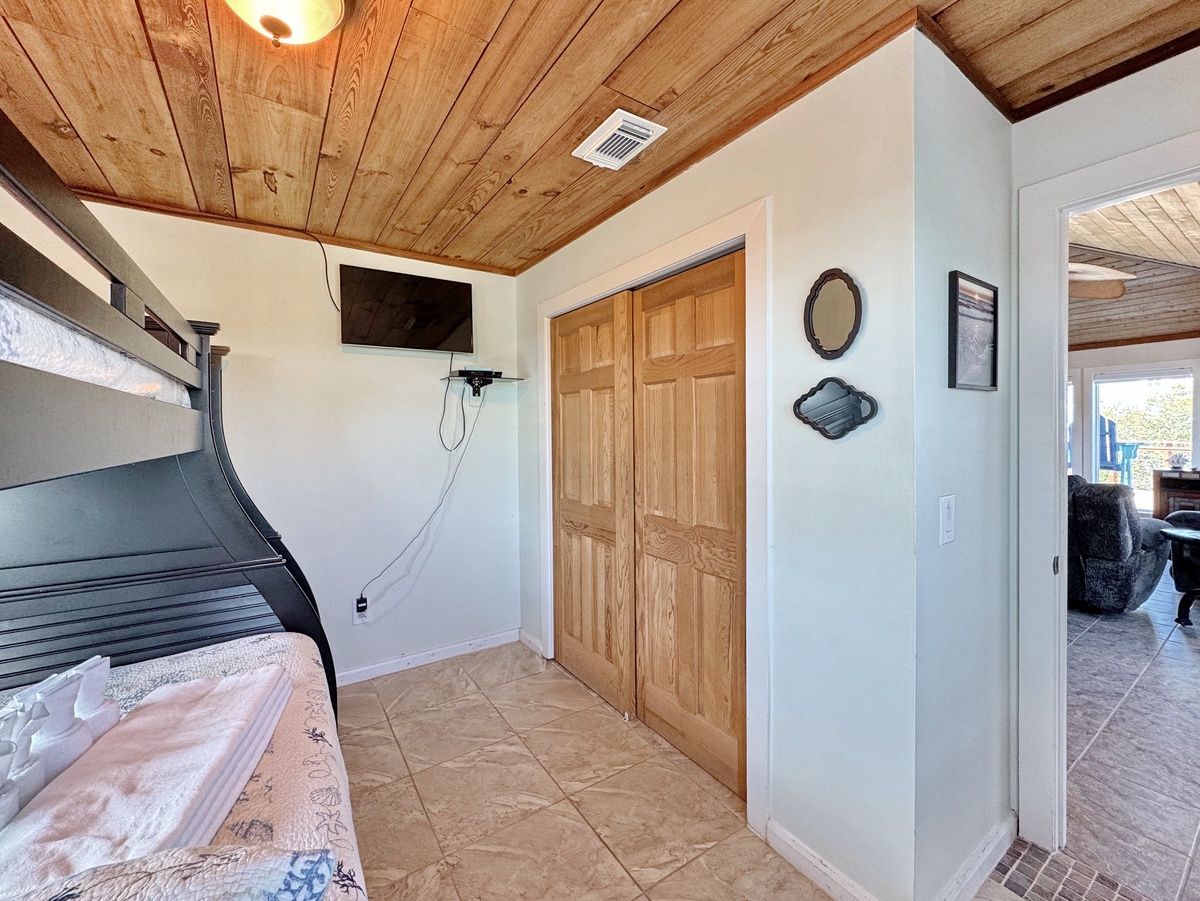 Your cozy bedroom features rustic wood ceilings, a comfortable bunk bed, and thoughtful decor touches that create a warm, welcoming retreat.
