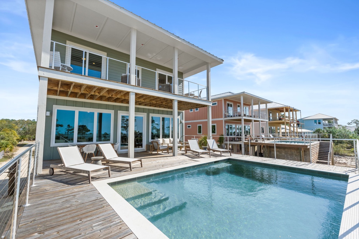 Modern waterfront home with private pool and expansive deck surrounded by coastal landscape.
