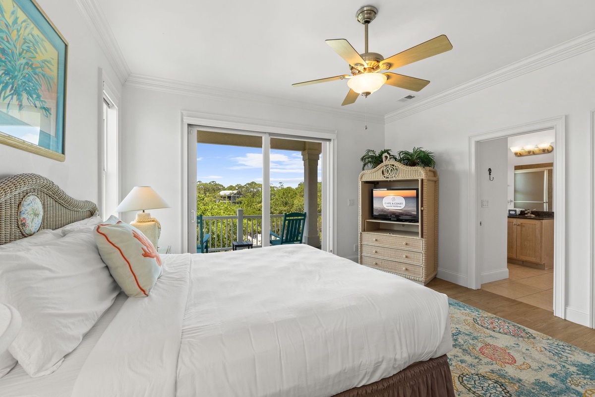 Your peaceful bedroom retreat features a ceiling fan for comfort, sliding doors opening to your private balcony, and soft coastal décor inviting relaxation after your day's adventures.